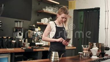 活泼开朗的女咖啡师在咖啡店用手机发短信